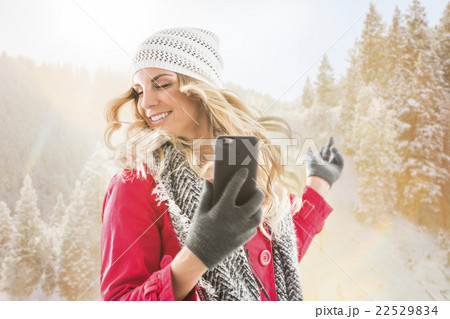 Young woman wearing winter clothing dancing with smart phone in hands Young woman wearing winter clothing dancing with smart phone in hands 22529834