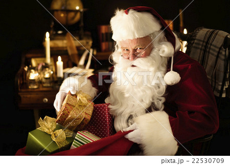 Santa Claus packing Christmas presents to sack 22530709