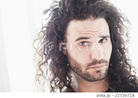 Portrait of young man with long curly hair 22530718