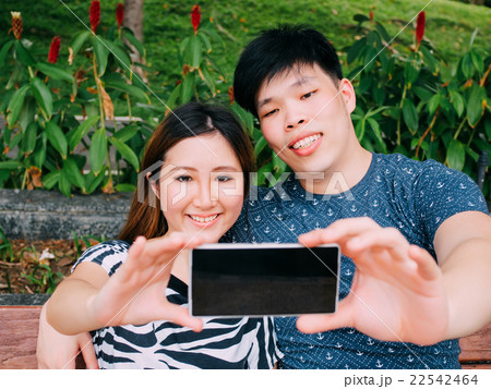 Asian couple taking a selfie photo in outdoor park Asian couple taking a selfie photo in outdoor park 22542464
