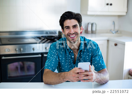 Portrait of young man using mobile phone in kitchen 22551072
