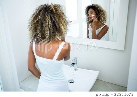 Young woman cleaning her face with sponge 22551075