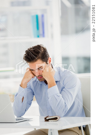 Tensed businessman sitting at table with laptop Tensed businessman sitting at table with laptop 22551081