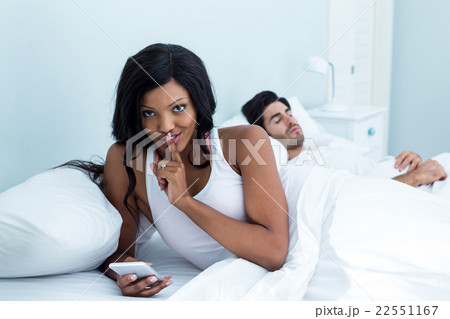 Woman checking her mobile phone while sleeping on bed 22551167