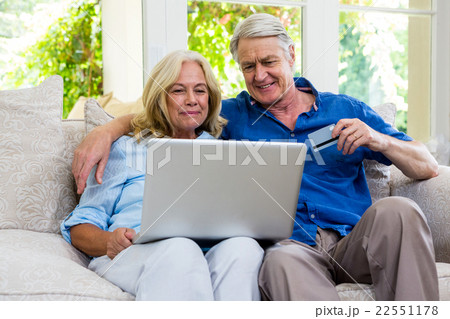 Senior couple using laptop while sitting on sofa at home Senior couple using laptop while sitting on sofa at home 22551178