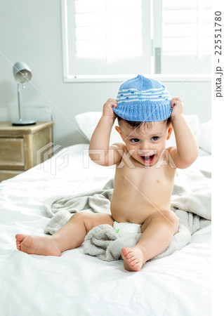 Cute baby boy wearing knit hat on bed Cute baby boy wearing knit hat on bed 22551780