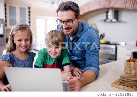 Father and kids using laptop in kitchen 22551935