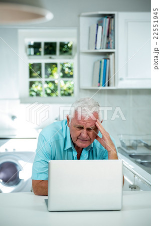 Worried senior man using laptop in kitchen Worried senior man using laptop in kitchen 22551945