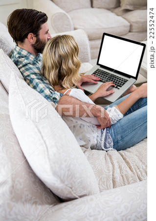 Couple using laptop while sitting on sofa 22552474