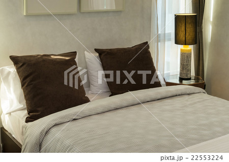 brown pillows on bed with lamp 22553224