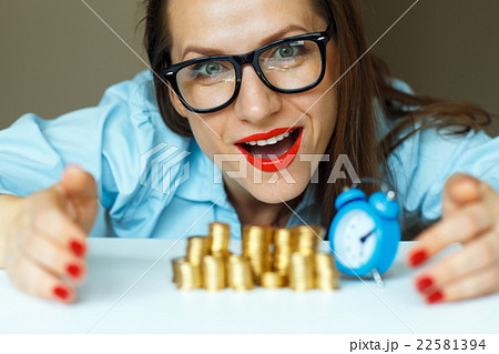 Smiling woman stacking gold coins into columns 22581394