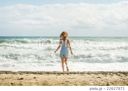 Young woman in blue denim jumpsuit walking to the 22627871