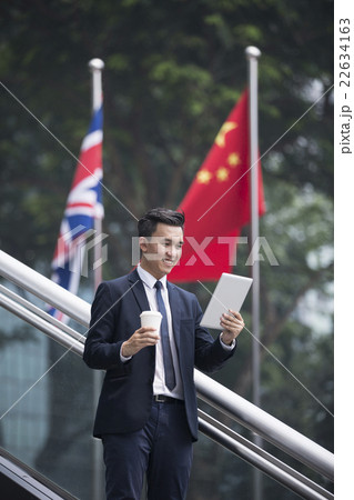 Chinese businessman with a tablet computer in front of flags. 22634163