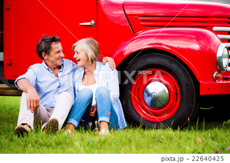 Senior couple sitting at the red vintage car Senior couple sitting at the red vintage car 22640425