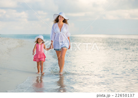 Mother and daughter walking on the beach 22650137