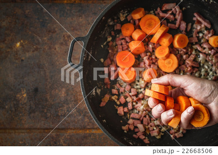 Adding carrots in the pan with bacon top view Adding carrots in the pan with bacon top view 22668506