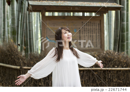 京都府京都市右京区嵯峨の竹林で深呼吸をしている笑顔の若い女性 22671744