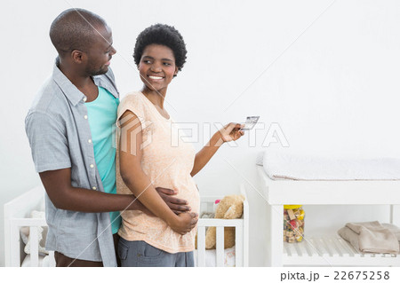 Pregnant couple holding ultrasound scan near baby cradle Pregnant couple holding ultrasound scan near baby cradle 22675258