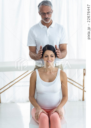 Pregnant woman receiving a head massage from masseur 22676447