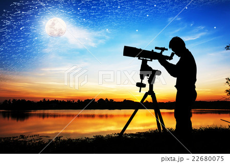 silhouette of young man looking through a telescope at the full 22680075
