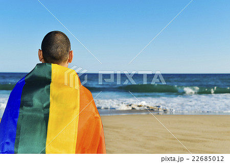 man wrapped in rainbow flag in front of the ocean man wrapped in rainbow flag in front of the ocean 22685012