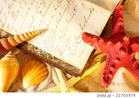 Seashells and old book on sand 22703974