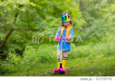 Little girl riding a colorful scooter Little girl riding a colorful scooter 22759742