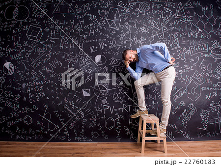 Man at step ladder, against big blackboard 22760183