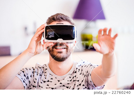 Man wearing virtual reality goggles, sitting in Man wearing virtual reality goggles, sitting in 22760240