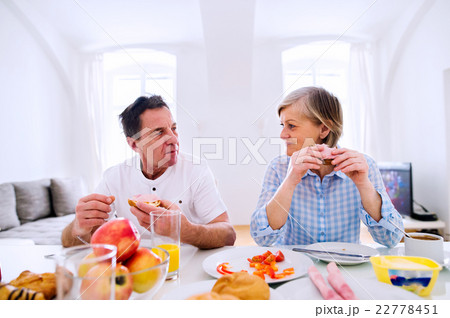Senior man and woman having breakfast. Sunny Senior man and woman having breakfast. Sunny 22778451