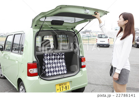 車に荷物を積む若い女性の写真素材