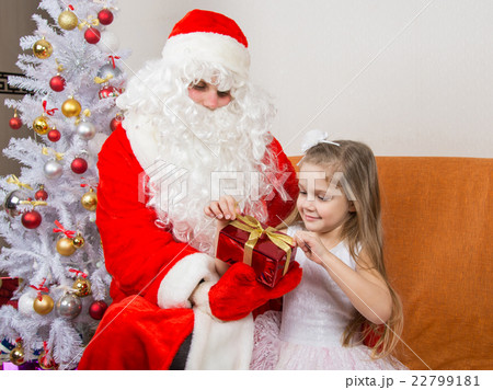 Girl unleashes a red ribbon gift that keeps Santa Claus in the hands of Girl unleashes a red ribbon gift that keeps Santa Claus in the hands of 22799181