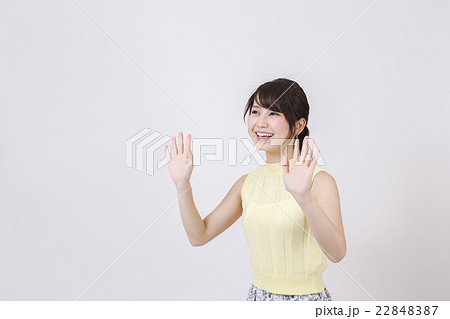 白い背景の前で両手を前に出している笑顔の若い女性の写真素材