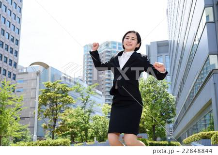 ビジネス街でジャンプする若い会社員の女性 22848844