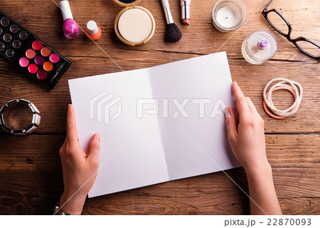 Hand of woman holding empty greeting card. Make-up 22870093