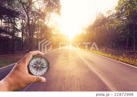 Hand holding compass on empty asphalt road Hand holding compass on empty asphalt road 22872906