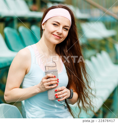 Young smiling sportswoman with bottle of water Young smiling sportswoman with bottle of water 22876417