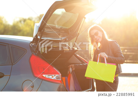 Woman putting her shopping bags into the car trunk 22885991