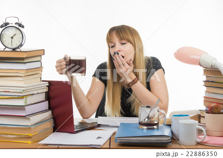 Girl student doing night yawns, holding another cup of coffee hands Girl student doing night yawns, holding another cup of coffee hands 22886350
