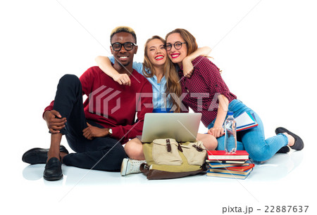 Three students sitting with books, laptop and bags isolated on w Three students sitting with books, laptop and bags isolated on w 22887637