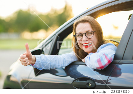 Young happy woman sitting in a car with thumb up Young happy woman sitting in a car with thumb up 22887839