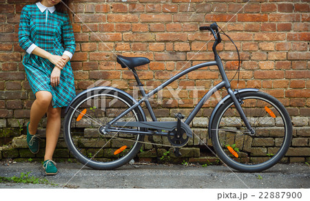 Black bicycle and a girl near it on the old brick wall backgrou Black bicycle and a girl near it on the old brick wall backgrou 22887900