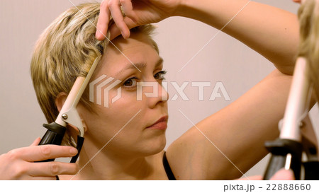 Short hair woman curls her hair with curling iron 22888660