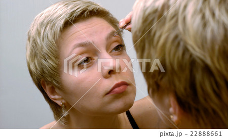 Woman plucks and pulls her eyebrows out at mirror Woman plucks and pulls her eyebrows out at mirror 22888661