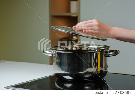 Person removing lid from cooking pot Person removing lid from cooking pot 22888686