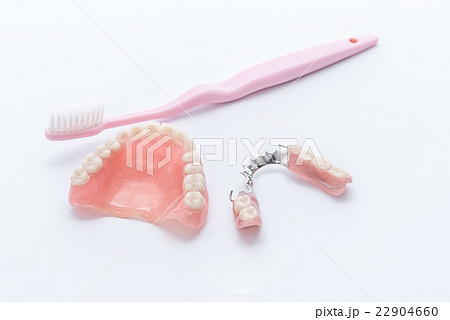 Acrylic dentures with toothbrush on white Acrylic dentures with toothbrush on white 22904660