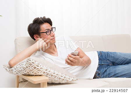 若い男性　スマホを持ちソファーに横になる 22914507