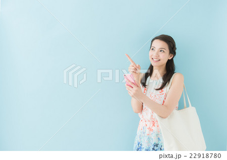スマホを操作する女性（ブルーバック） 22918780