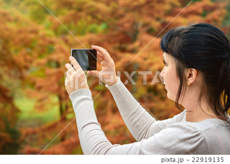 Woman taking pictures with mobile phone 22919135