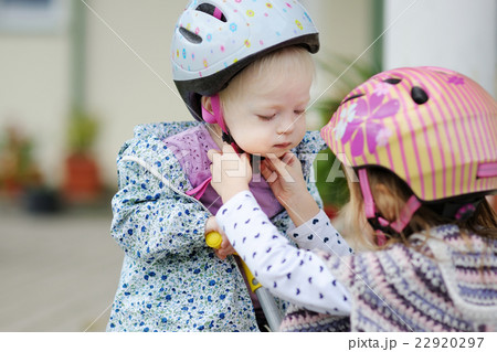Little girl hepling her sister to put a helmet Little girl hepling her sister to put a helmet 22920297